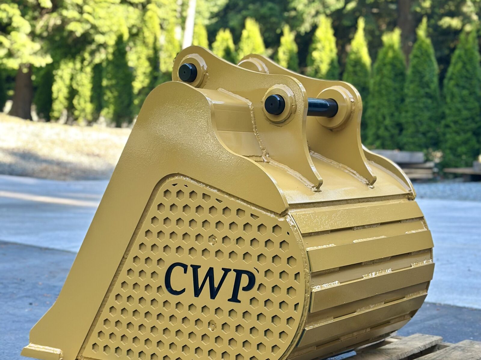 Finished CAT-yellow excavator bucket built by Cascade Wear Parts, showing the rolled shell and wear straps