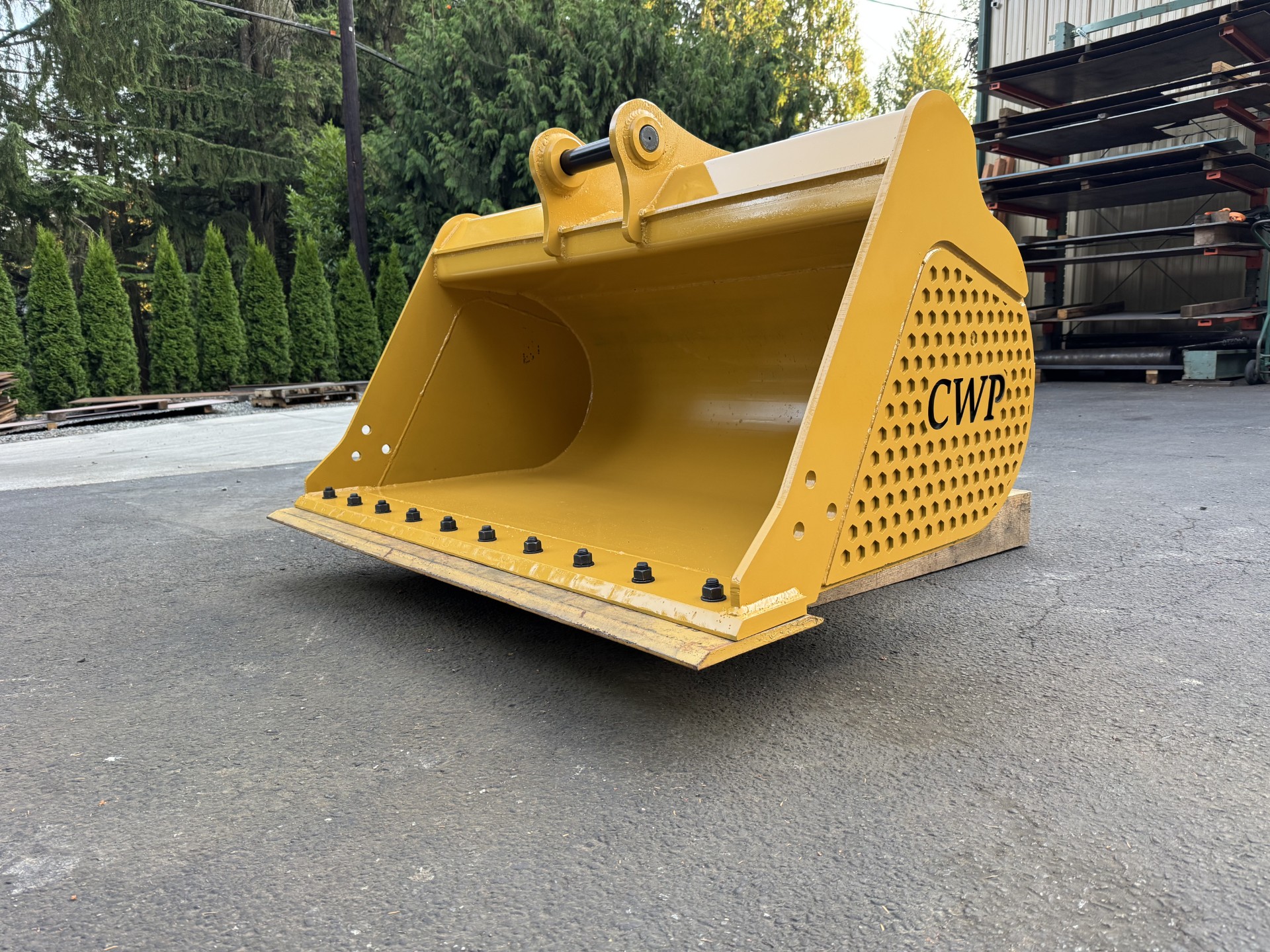 New CWP 60-inch cleanout bucket for a Cat 308 excavator, finished in CAT yellow outside the Cascade Wear Parts shop