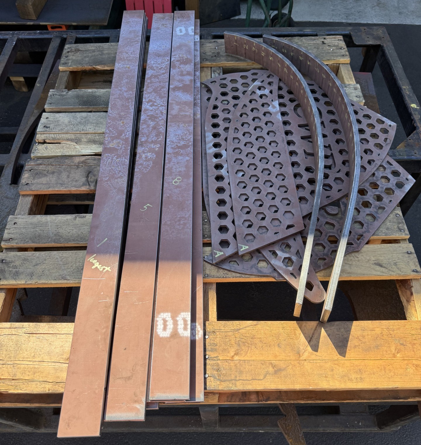 Complete custom wear package on a pallet—wear bars and hex-perforated Power Plate panels cut, formed, and labeled for installation