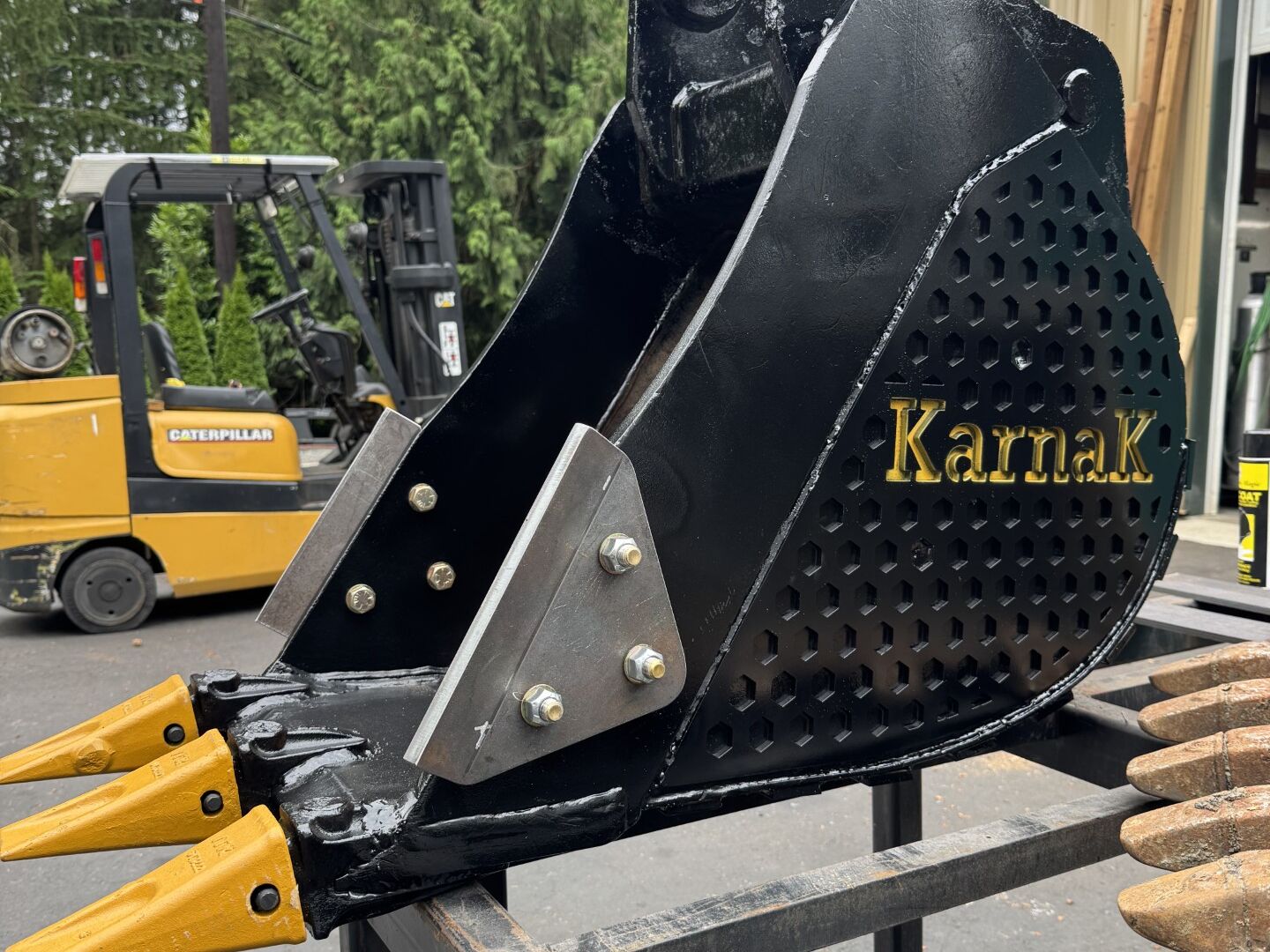 Black bucket with the customer's name plasma-cut into the cheek plate, new teeth, and side cutters