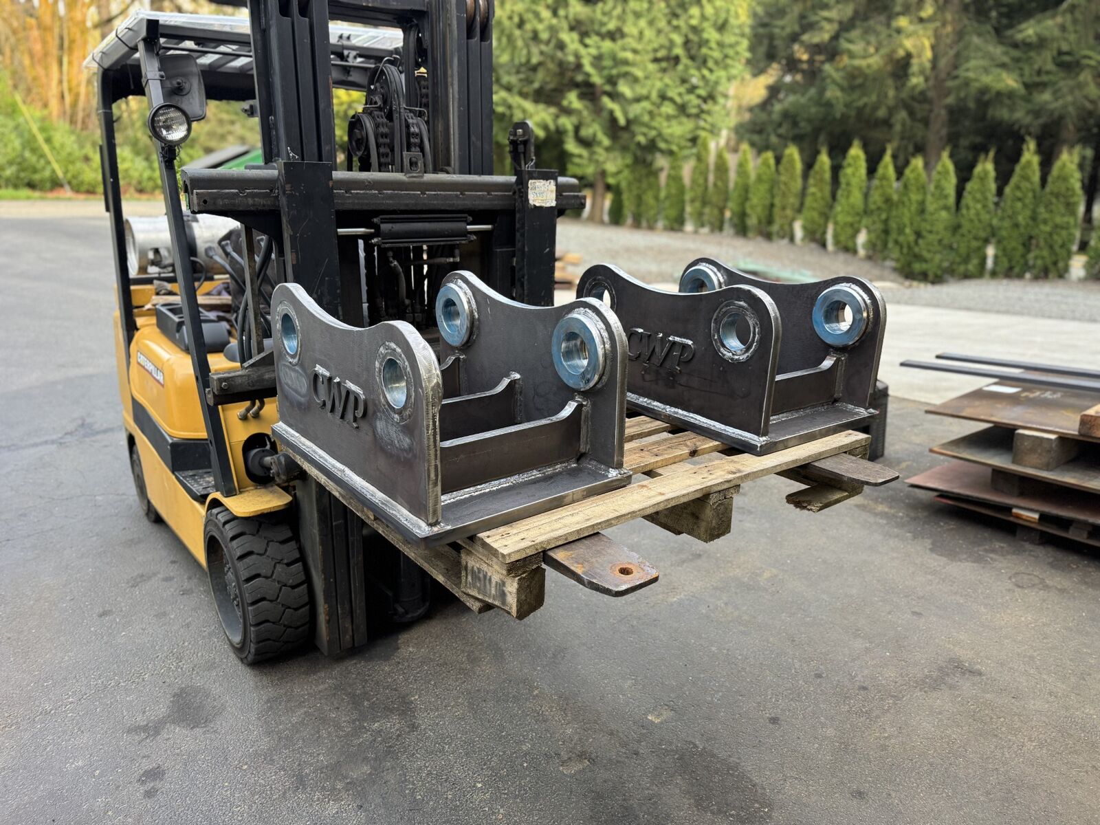 Pair of CWP quick-coupler plate adapters with precision machined bores on a forklift