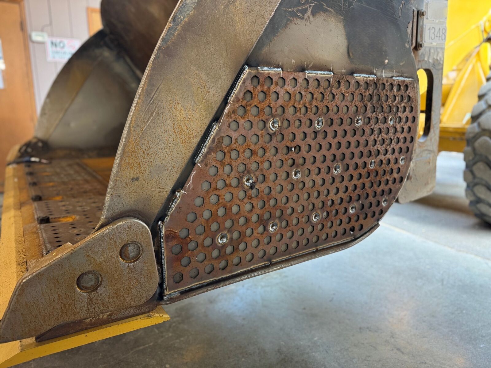Hex-perforated Power Plate corner wrap freshly welded onto a loader bucket