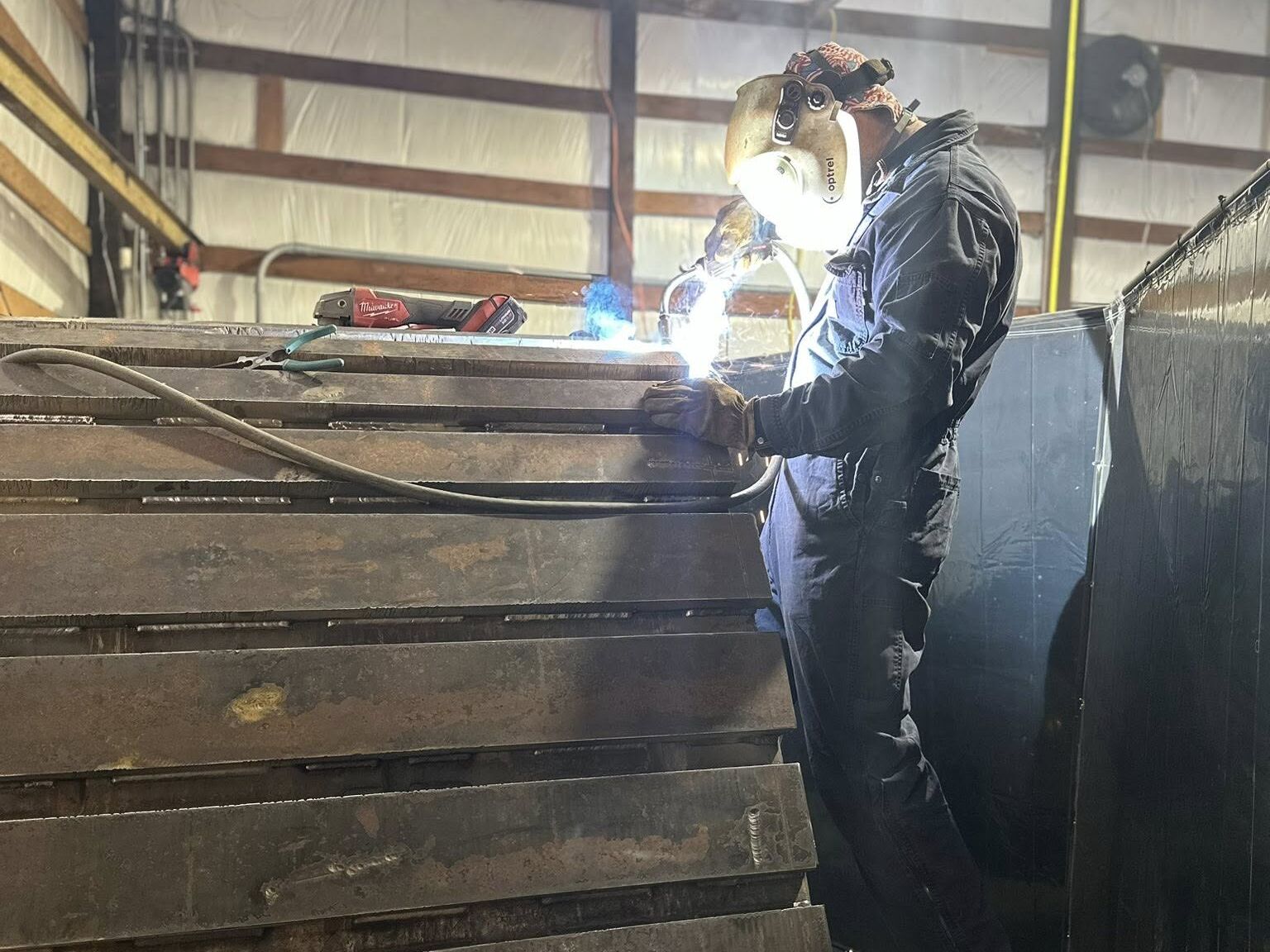 Stitch welding a full stack of new wear bar panels in the CWP shop
